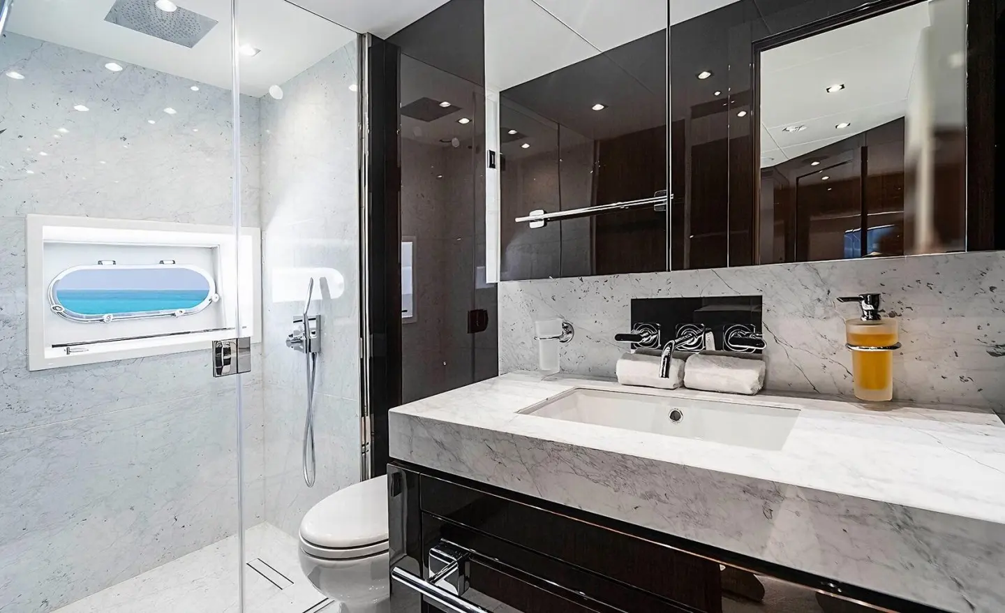 Bathroom aboard Quantum yacht with dark wood cabinets, white sink, and glass shower