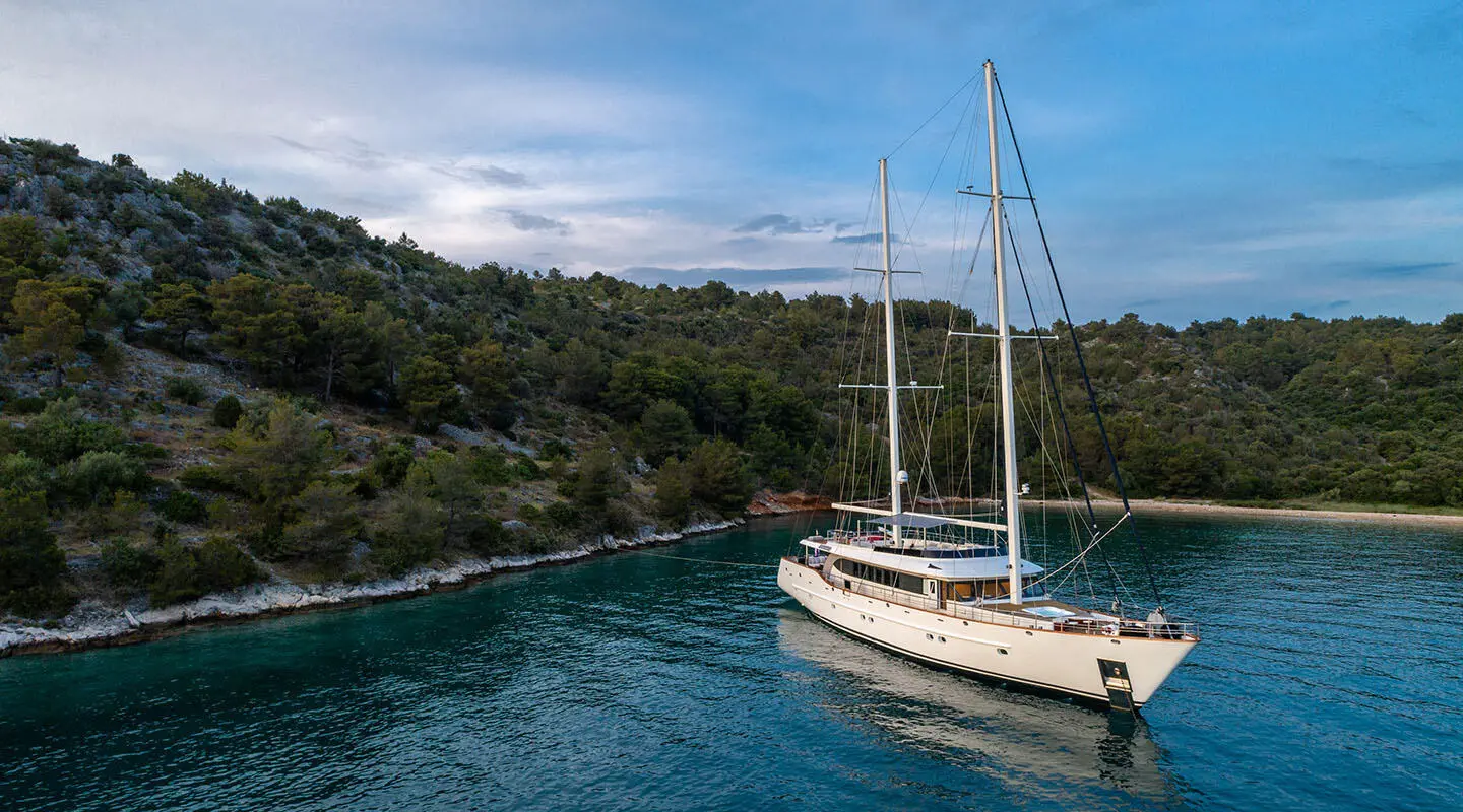 Navilux sailing yacht anchored in a secluded turquoise bay with forested cliffs