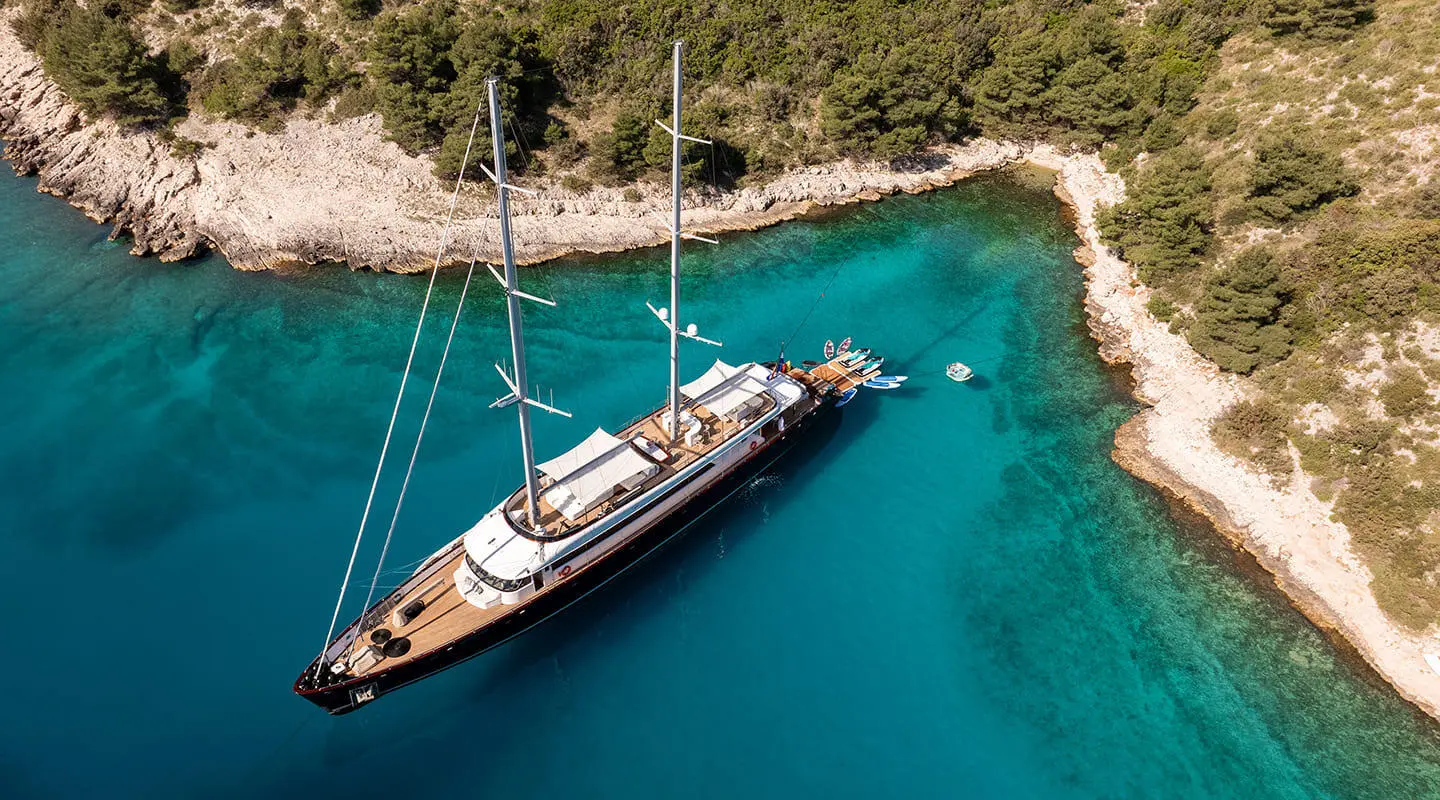 Nocturno yacht in clear water, motor yacht with sails stowed, docked near piers