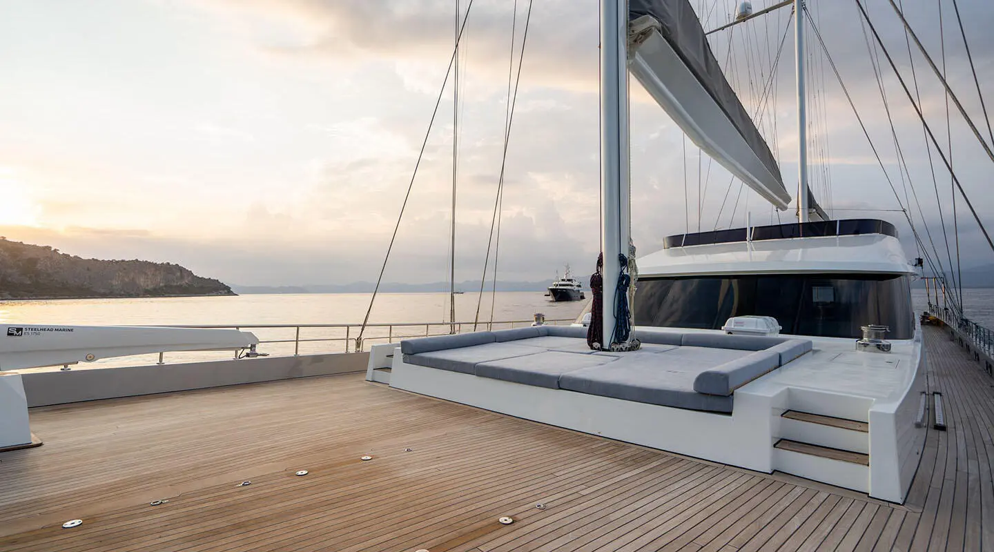 Yacht De Love docked at sunset with sails and wooden deck