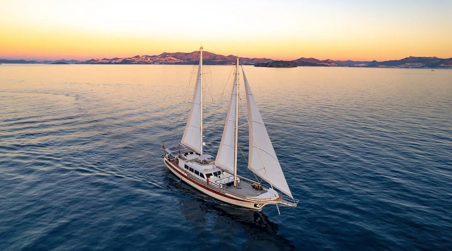 Double Eagle yacht sailing at sunset with white sails on calm sea