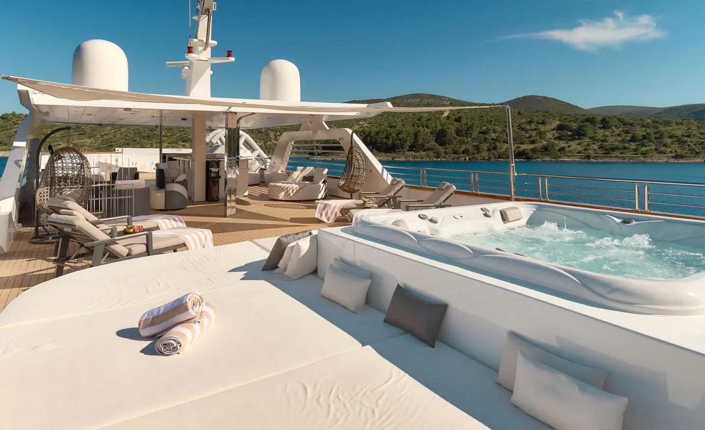 Spacious upper deck with loungers, seating areas and a pool on a luxury yacht