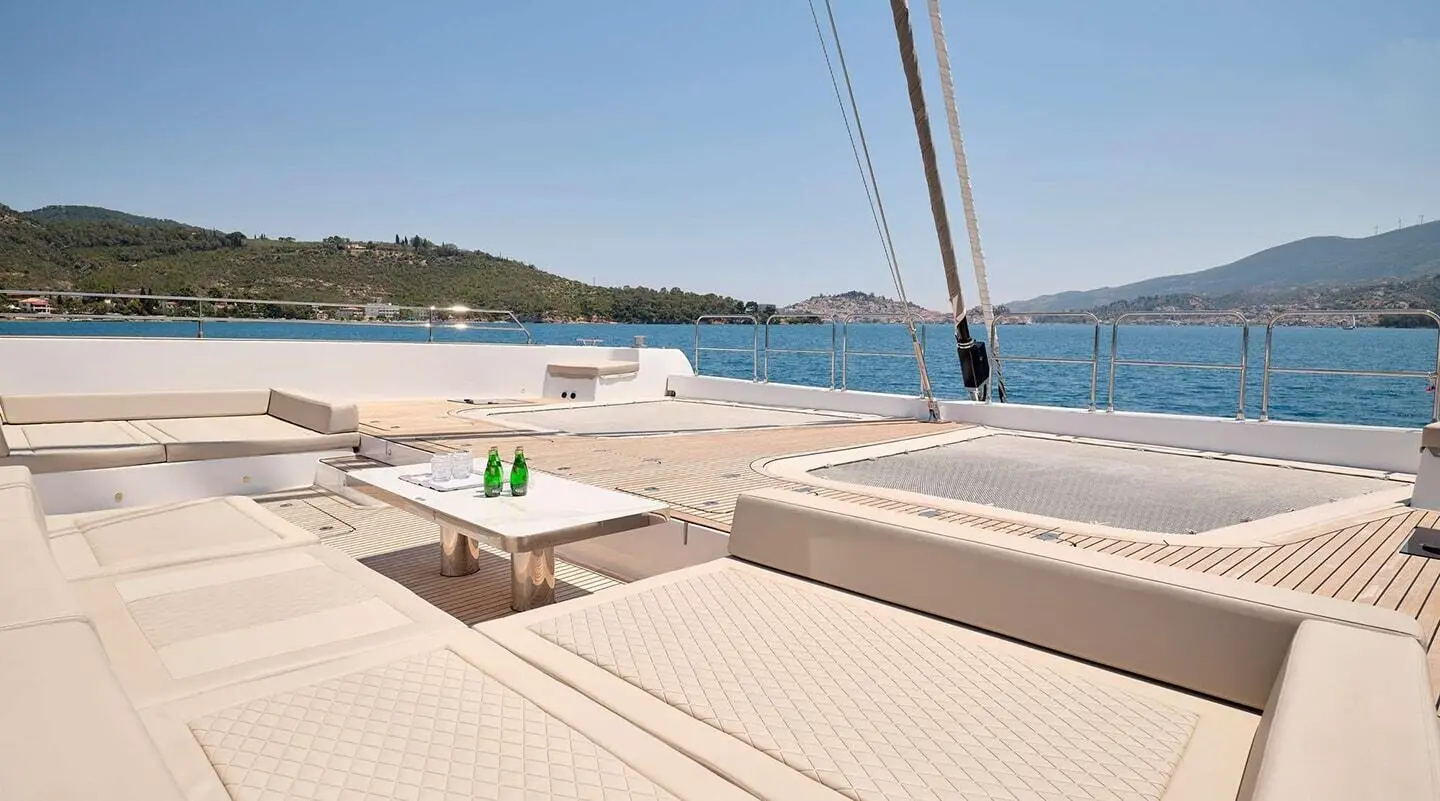 Sunlit yacht deck on Genny with loungers, table, and sea view