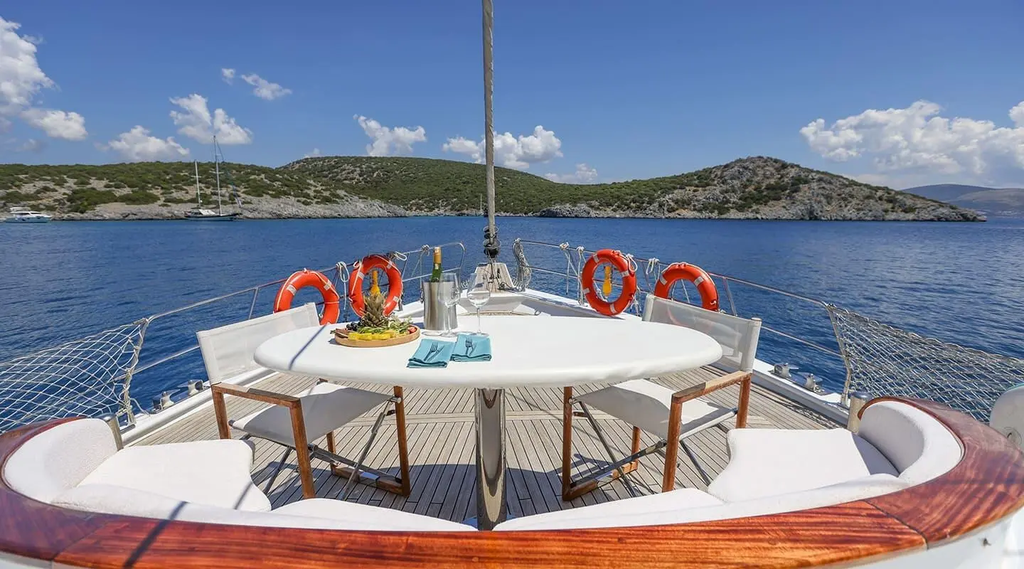 Gazella yacht deck with table set for guests, red lifebuoys, blue sea horizon