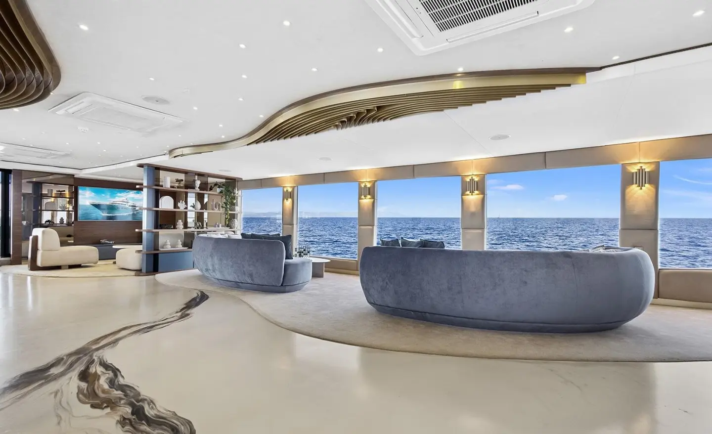 Yacht Bella salon seating area with curved blue cushions and wooden railing