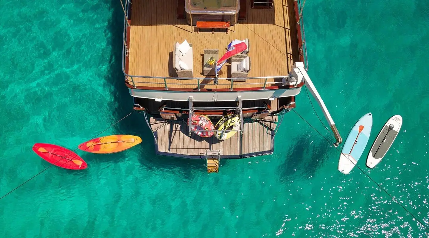 A luxury yacht Luna at sunset, wooden deck, sunlit water, anchored near shore