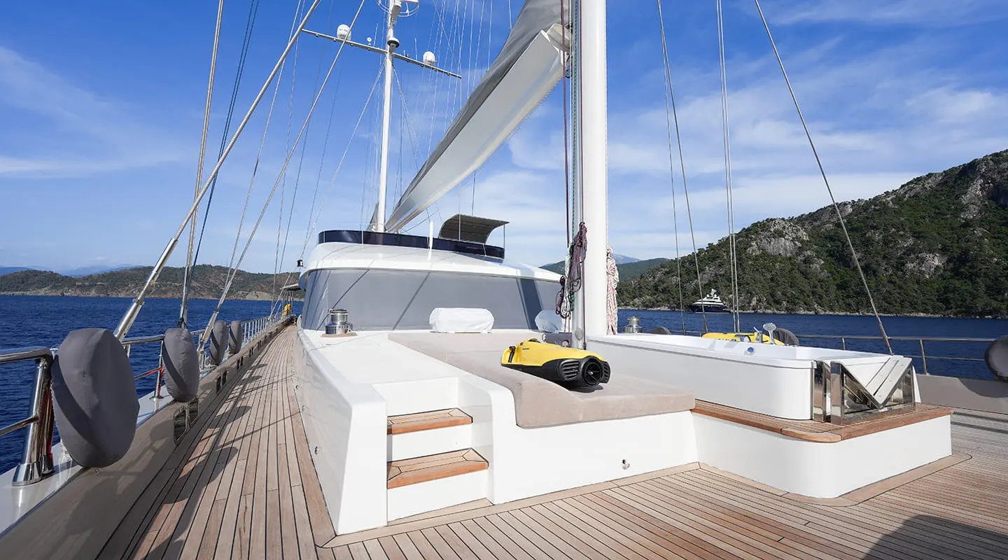 A luxury yacht deck with white railings and seating, blue sea beyond