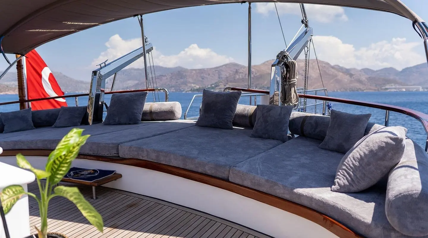 Nevra Queen yacht deck at sunset with blue cushions and mountains in distance