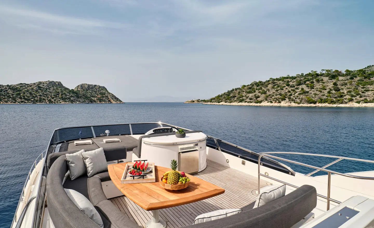 Sunlit aft deck of M Five yacht with seating area and wooden table by calm sea