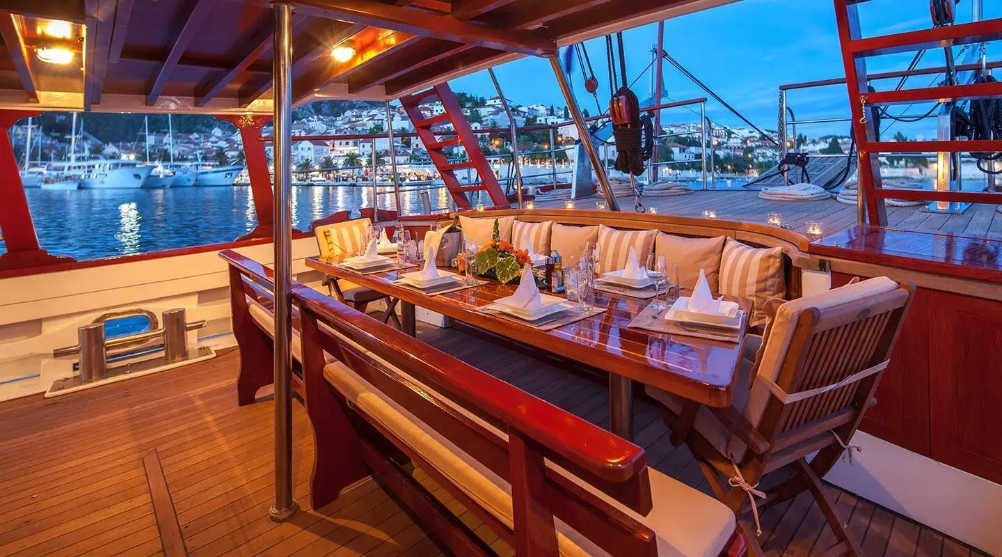 Romanca gulet dining area on aft deck with wooden benches and table set