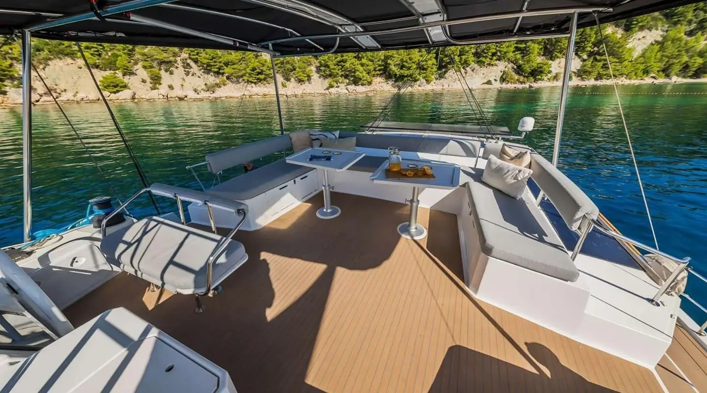 Sunlit yacht deck with lounge seating, white cushions, and wooden flooring
