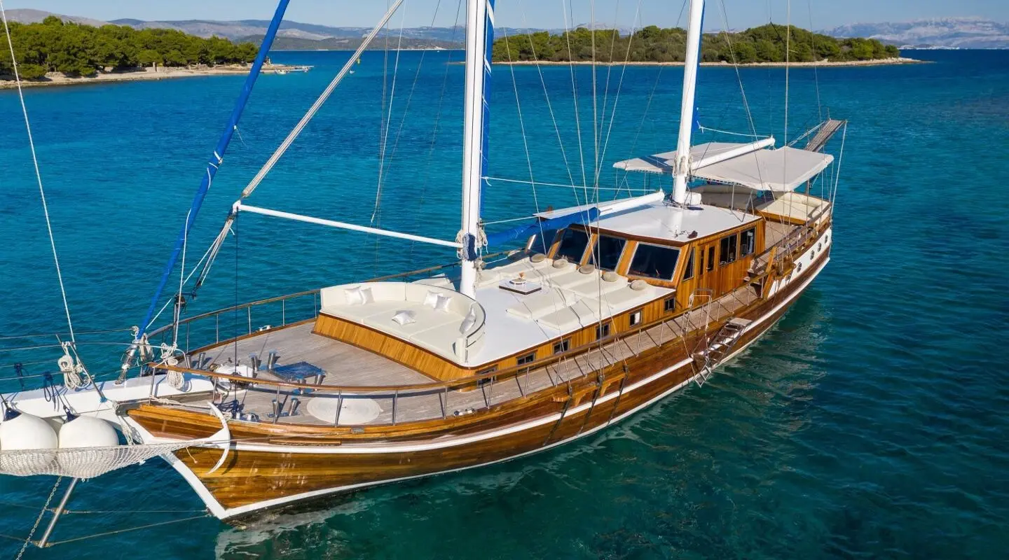 Andi Star yacht anchored near turquoise waters with wooden deck and sails