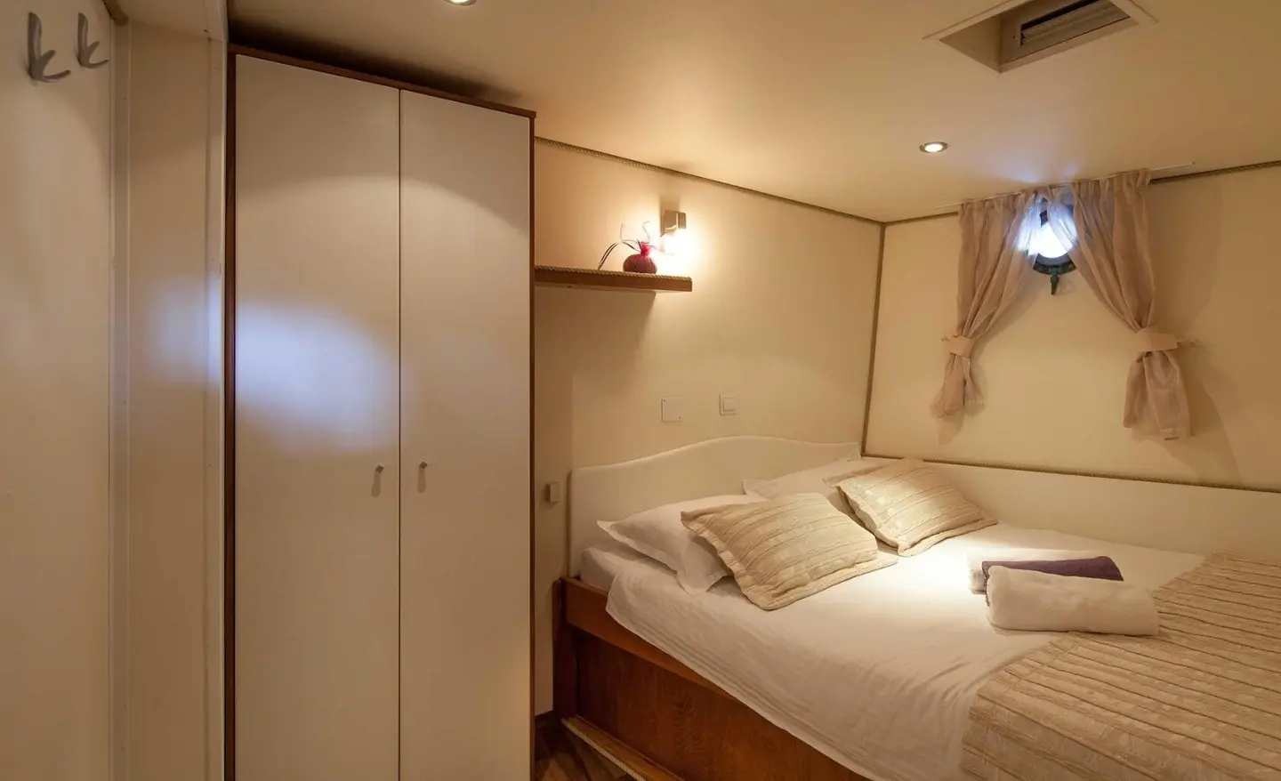 Bedroom with double bed, wardrobe, and sheer curtain window visible