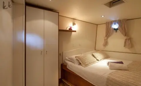 Bedroom with double bed, wardrobe, and sheer curtain window visible