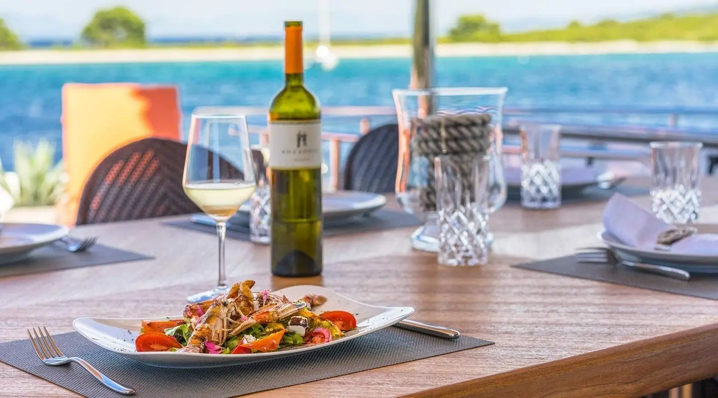 Seventh Sense yacht table set with wine bottle and plates on deck