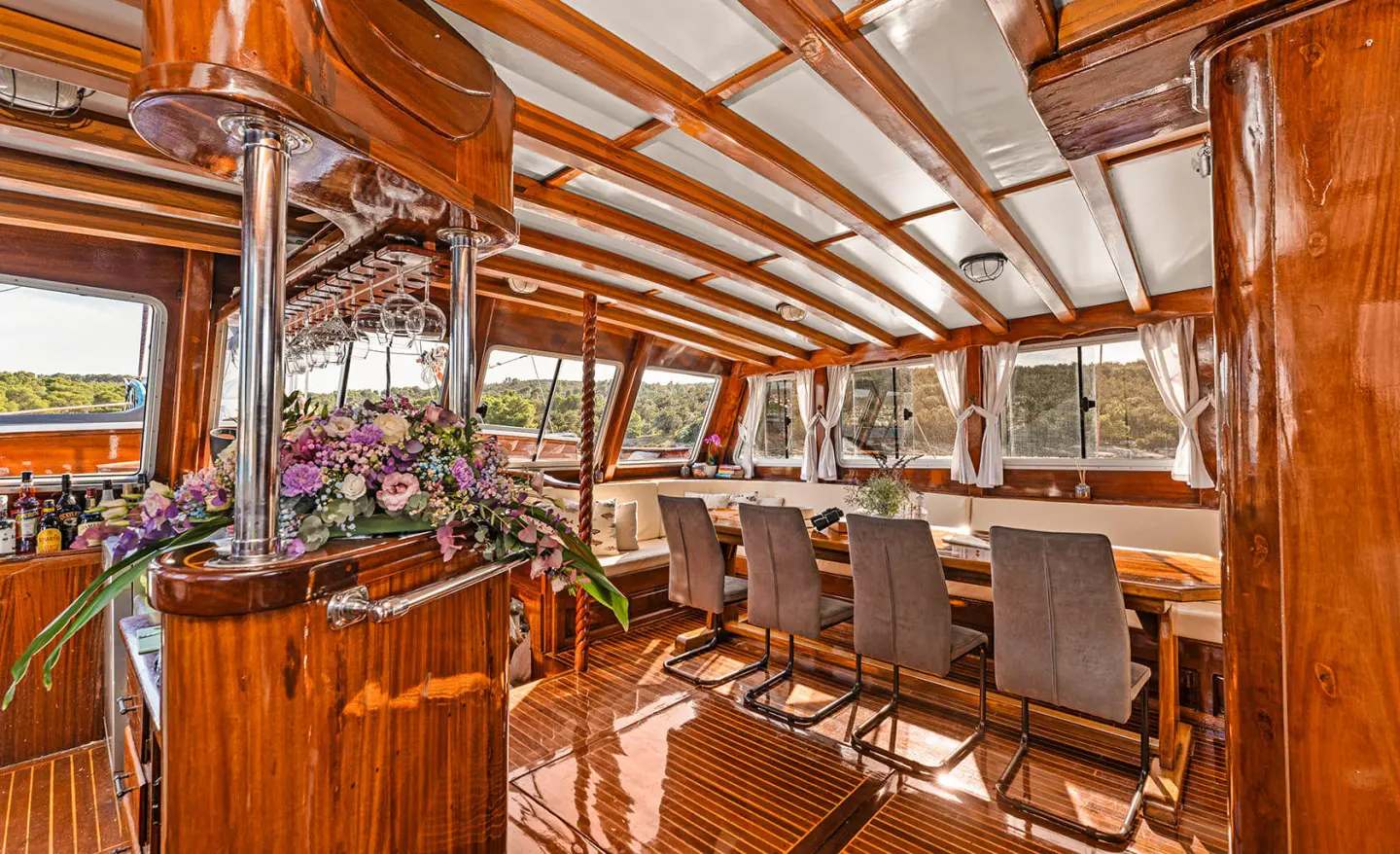 Luxurious yacht interior with polished wood, drink bar, and seating under a striped canopy