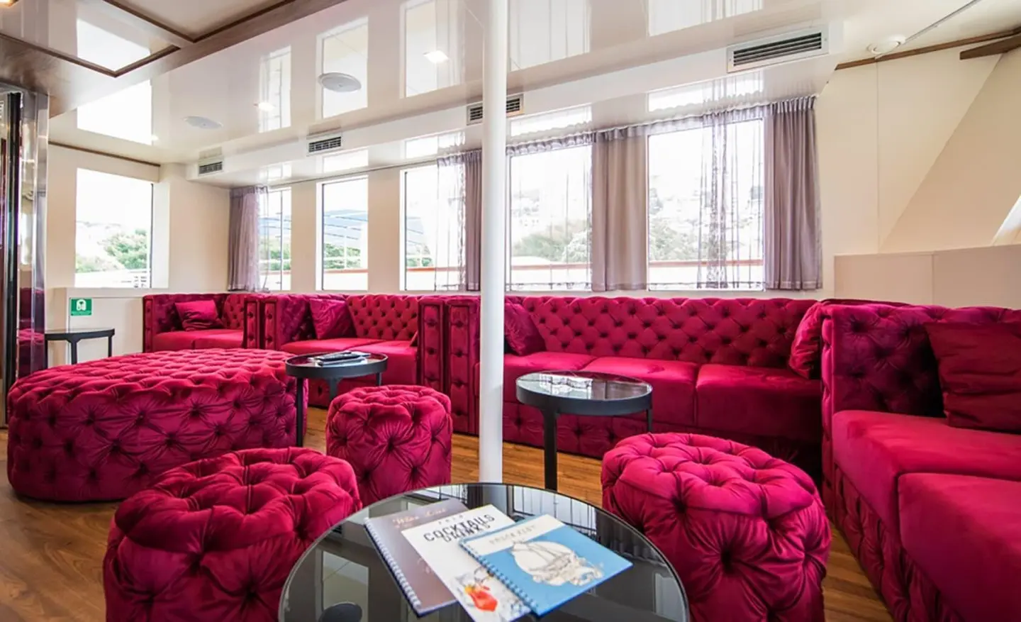 Luxurious red velvet lounge aboard Yolo yacht, sunlit windows and table
