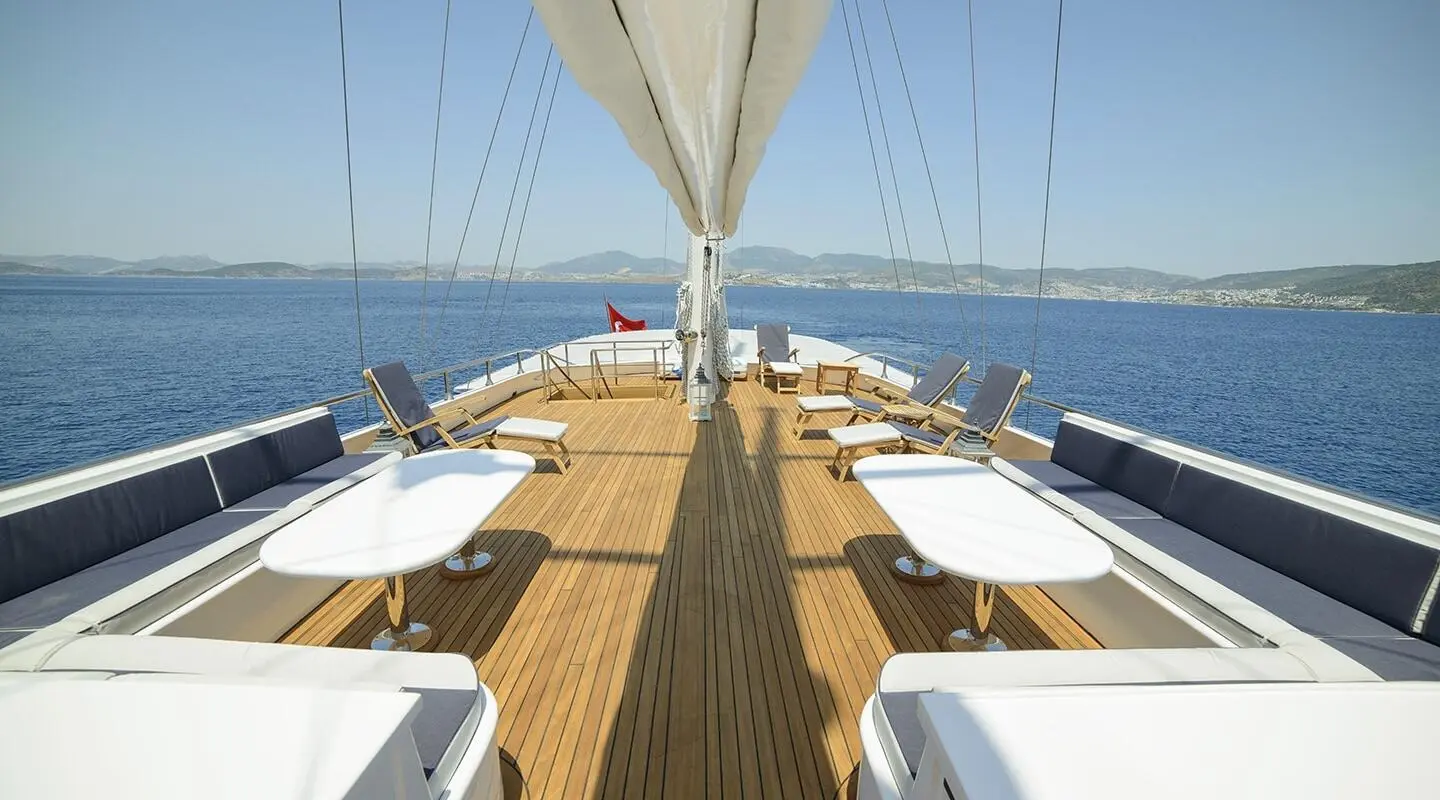 View down the teak deck of a luxury yacht with sun loungers and table settings