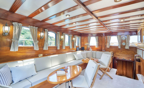 Luxurious Libra yacht interior: wood-paneled salon with white seating, hanging windows, and soft curtains