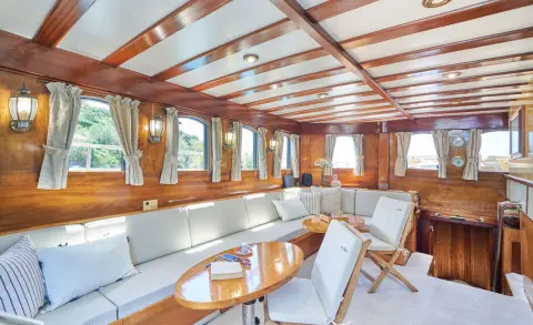 Luxurious yacht Libra interior with wooden ceiling, seating, and tables during daytime
