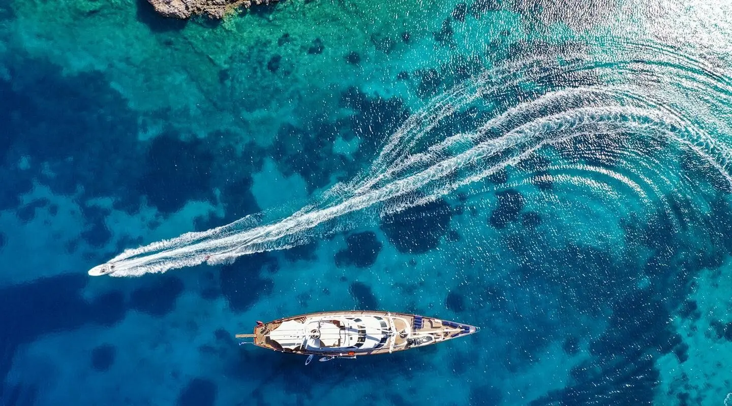 Aerial view of a luxury motor yacht Tamarita cruising blue sea with wake trails