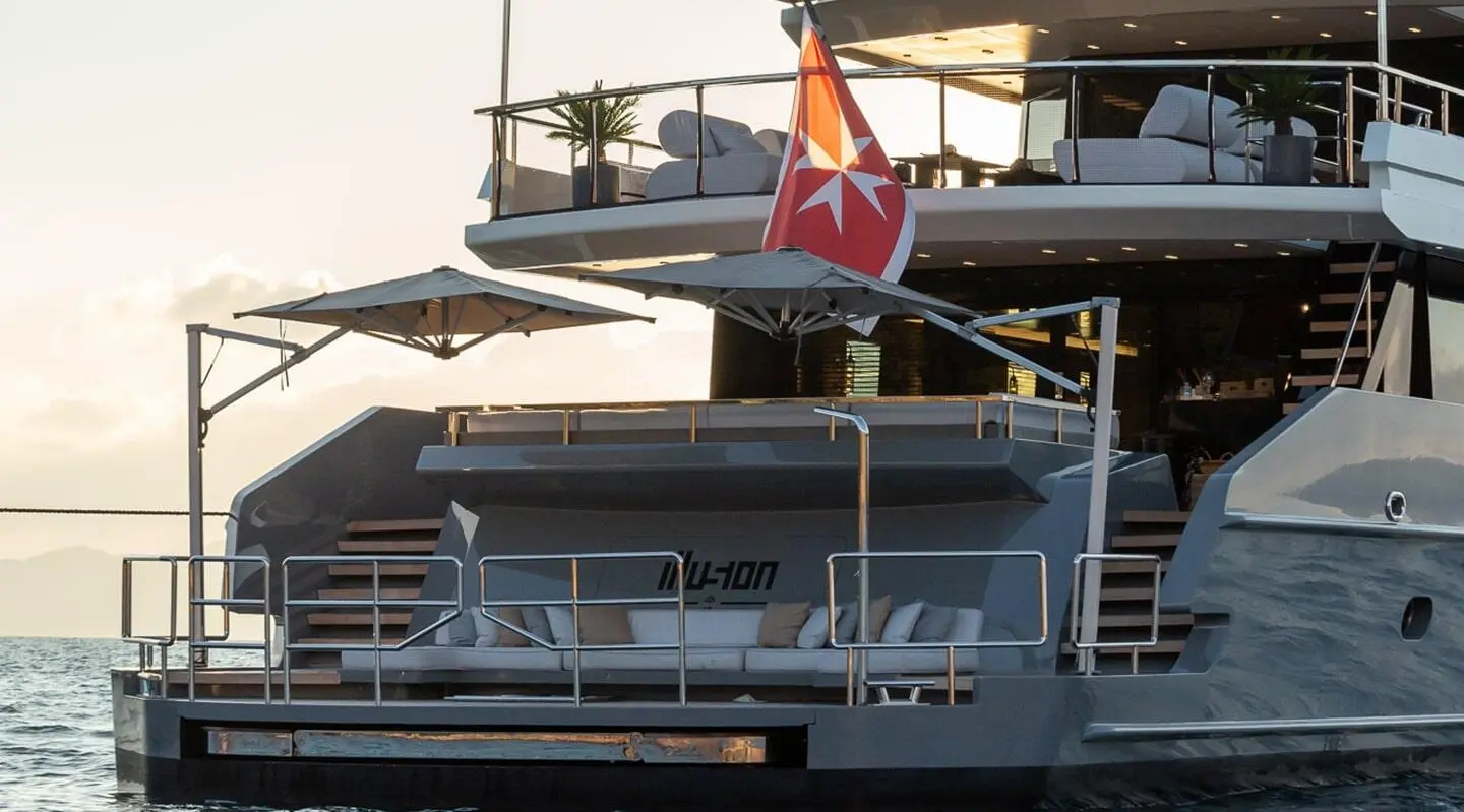 Illusion II yacht moored with sails and flag, anchored at dusk