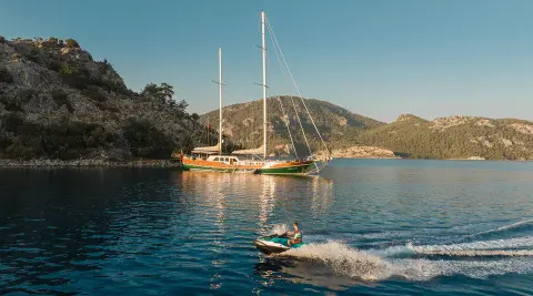 La Bella Vita yacht anchored near rocky coastline at sunset with calm blue water