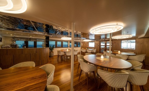 Olimp yacht interior dining area with warm wood tones and circular pendant lighting