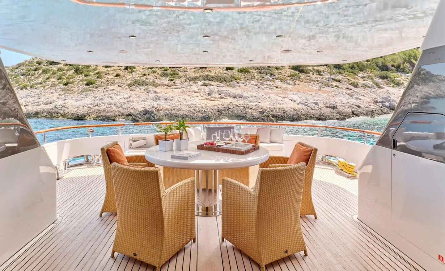 Mobius yacht deck dining area with wicker chairs around a table by the sea