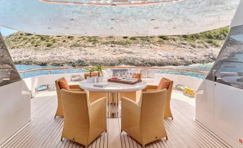 Mobius yacht deck dining area with wicker chairs around a table by the sea