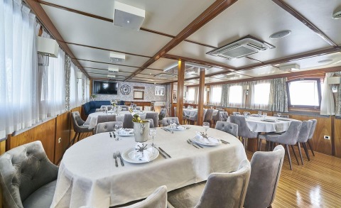 Amorena luxury yacht dining salon with round table setting and champagne cooler