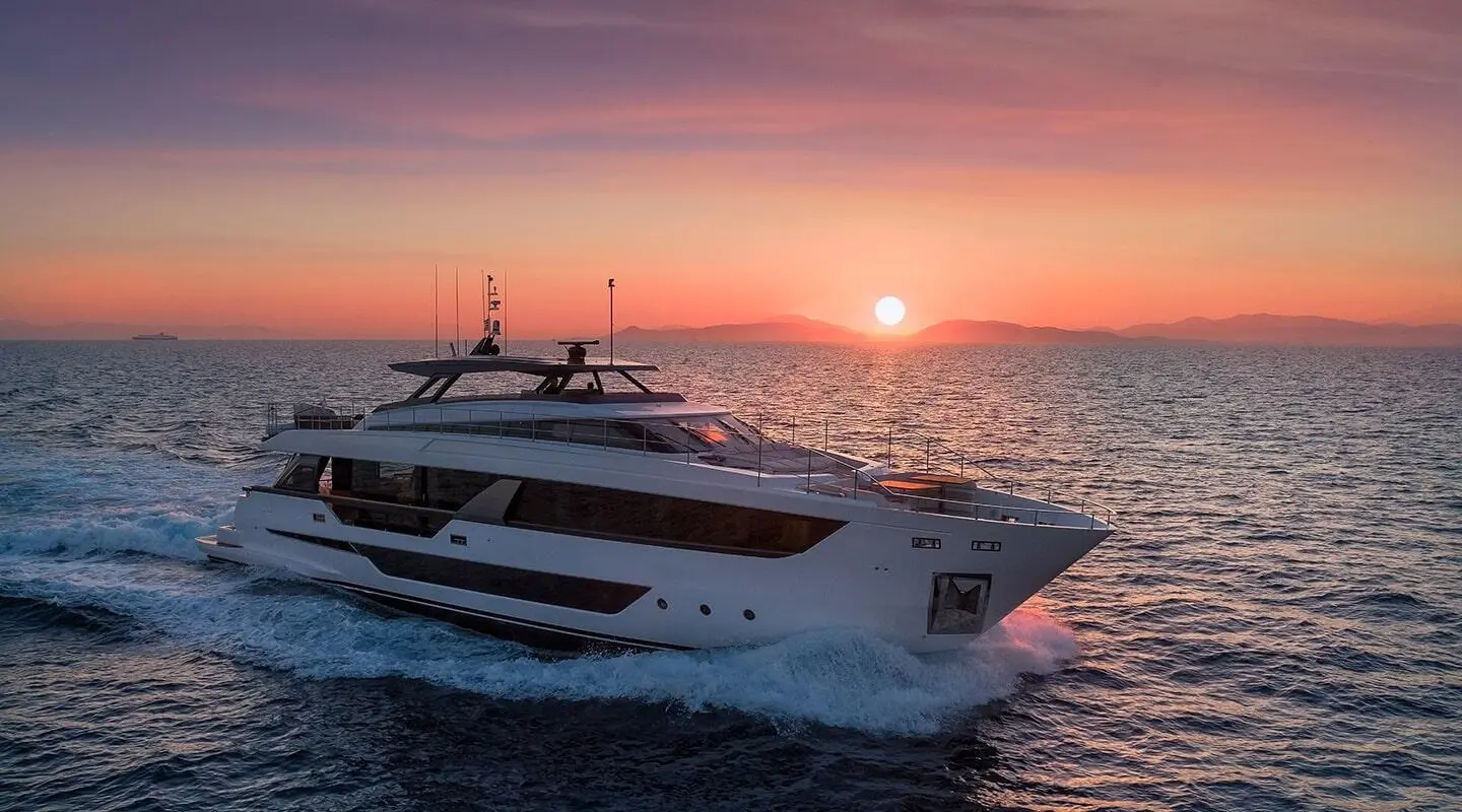 Spica yacht gliding at sunset with calm sea and orange sky behind