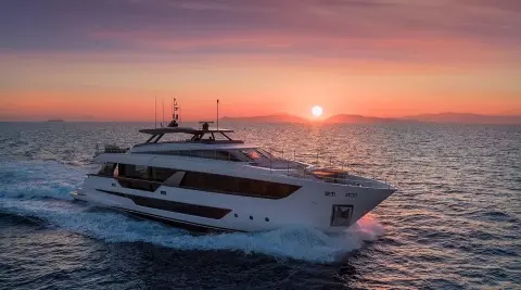 Spica yacht gliding at sunset with calm sea and orange sky behind