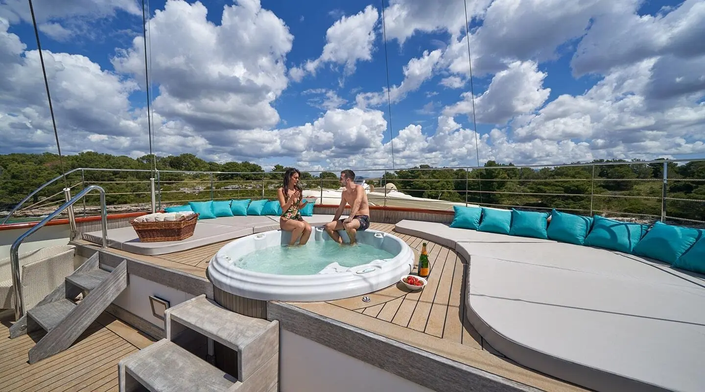 Casablanca yacht on deck with a circular jacuzzi and turquoise cushions, coastal landscape