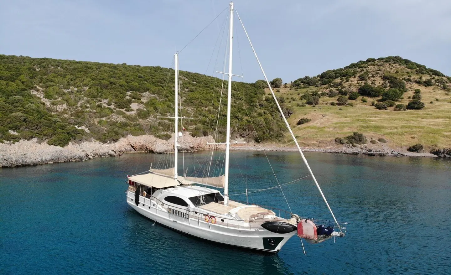 Gulet Queen Of Sea anchored in blue water near rocky coast
