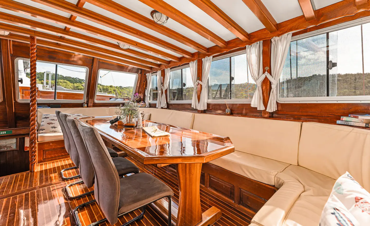 Luxurious yacht charter with wooden deck seating under a striped canopy at sunset