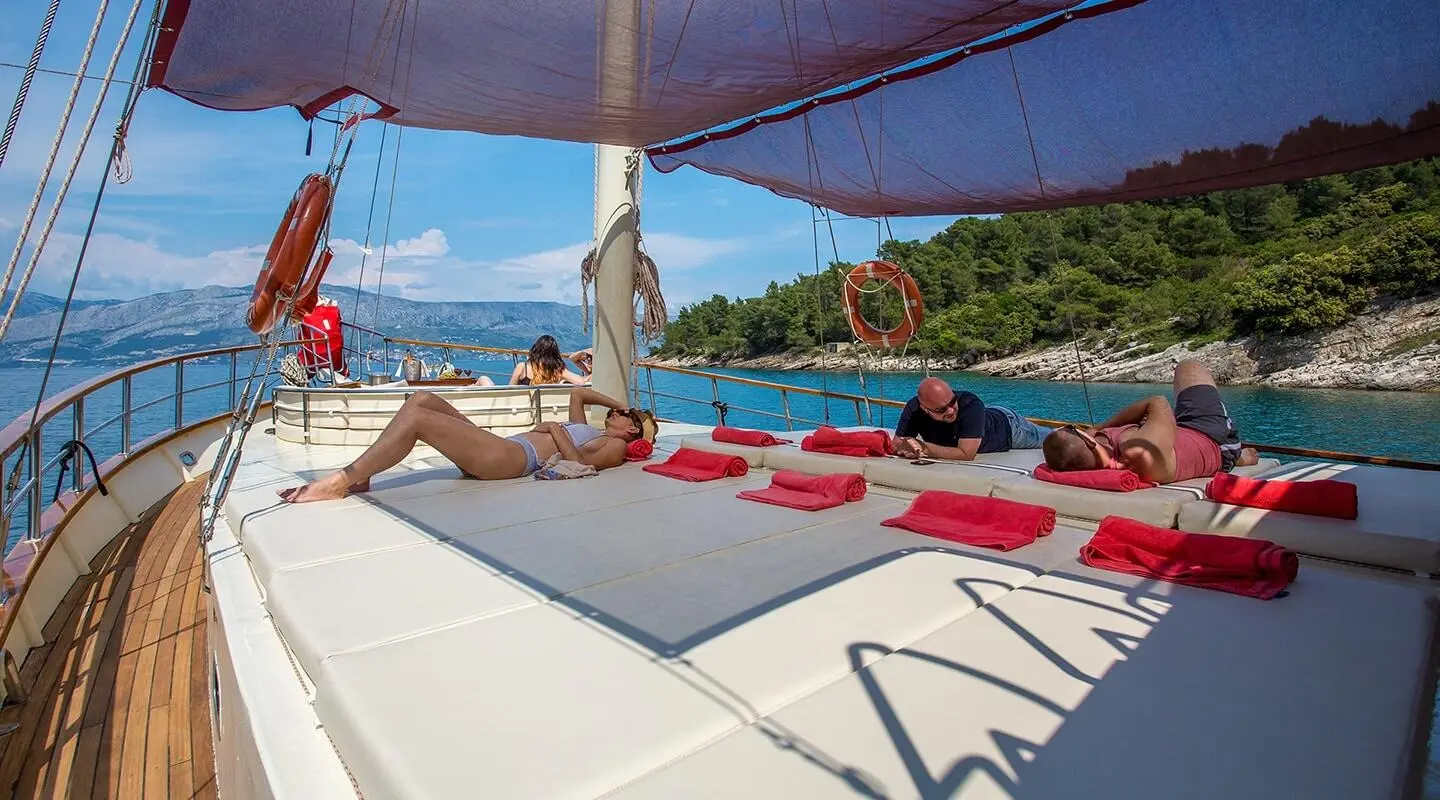 Gulet Altair sun deck with people lounging on cushioned white seating
