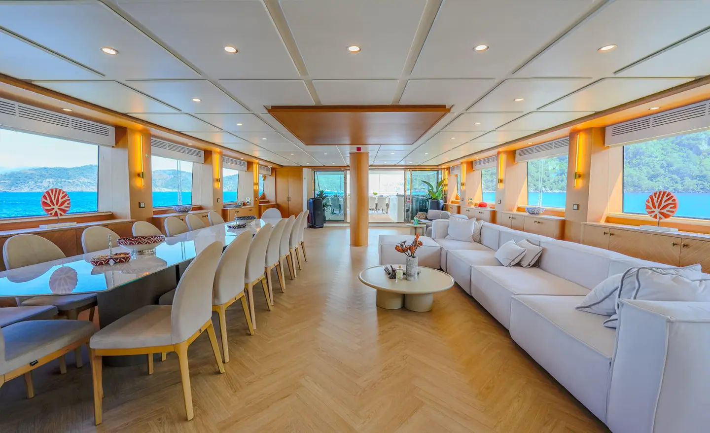 Luxurious yacht saloon interior with wooden floors, large windows, and seating