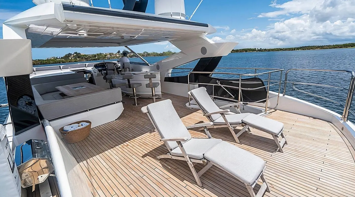 Yacht Quantum flybridge with sun loungers on wooden deck overlooking blue sea