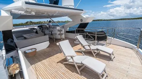 Yacht Quantum flybridge with sun loungers on wooden deck overlooking blue sea