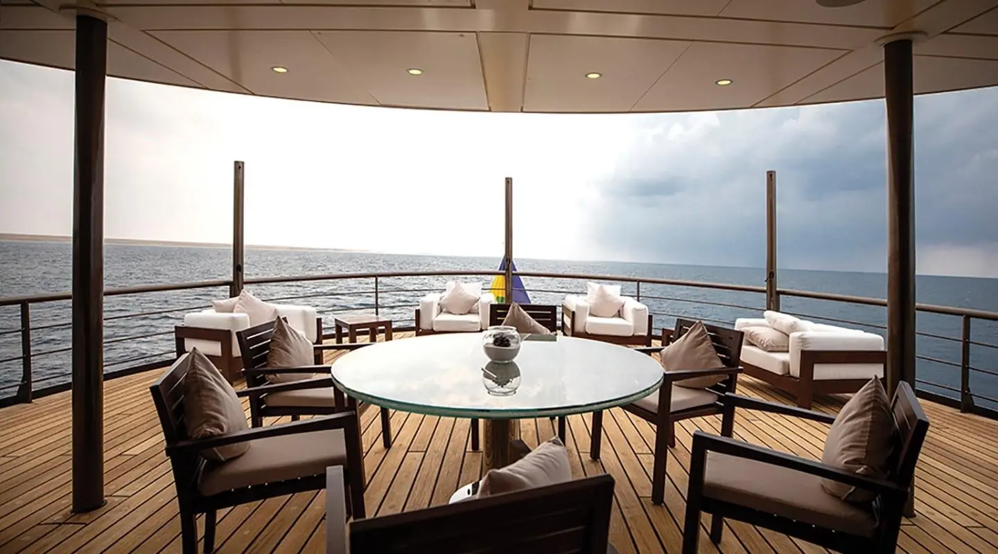 Chakra luxury yacht deck by the water with a round table and chairs