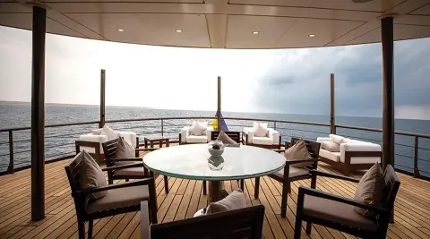 Chakra luxury yacht deck by the water with a round table and chairs