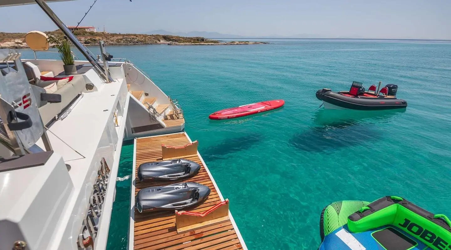 Astoria yacht deck with sun loungers and turquoise sea, kayaks nearby at sunset