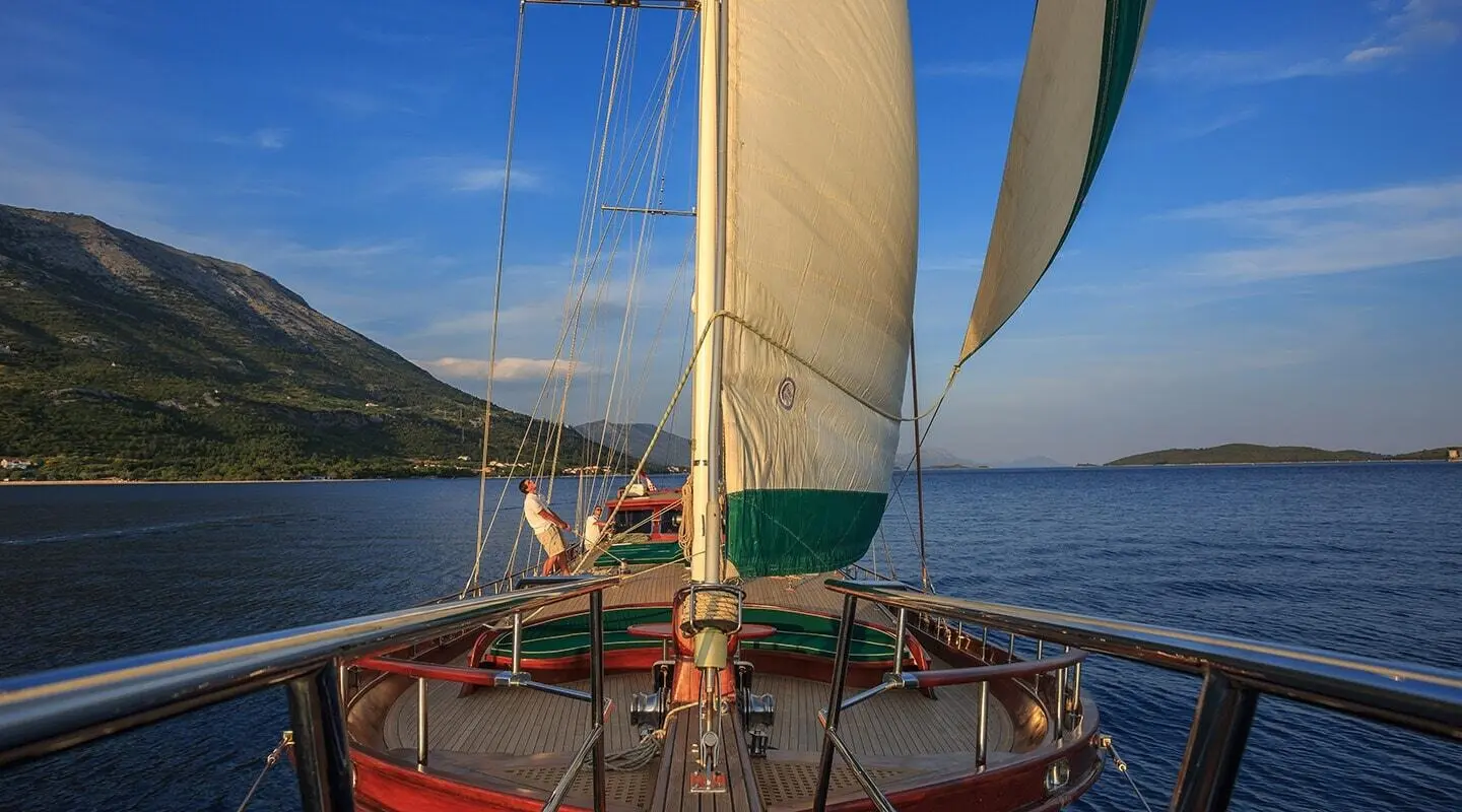 View from boat bow of Carpe Diem 7 gulet with sail raised at sea harbor