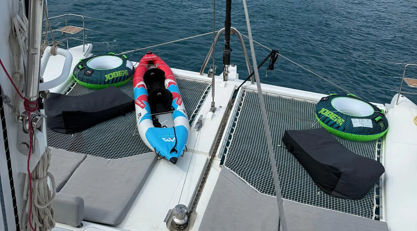 Yacht Atlantis deck view with a blue and white inflatable paddleboard on the bow, calm sea in background