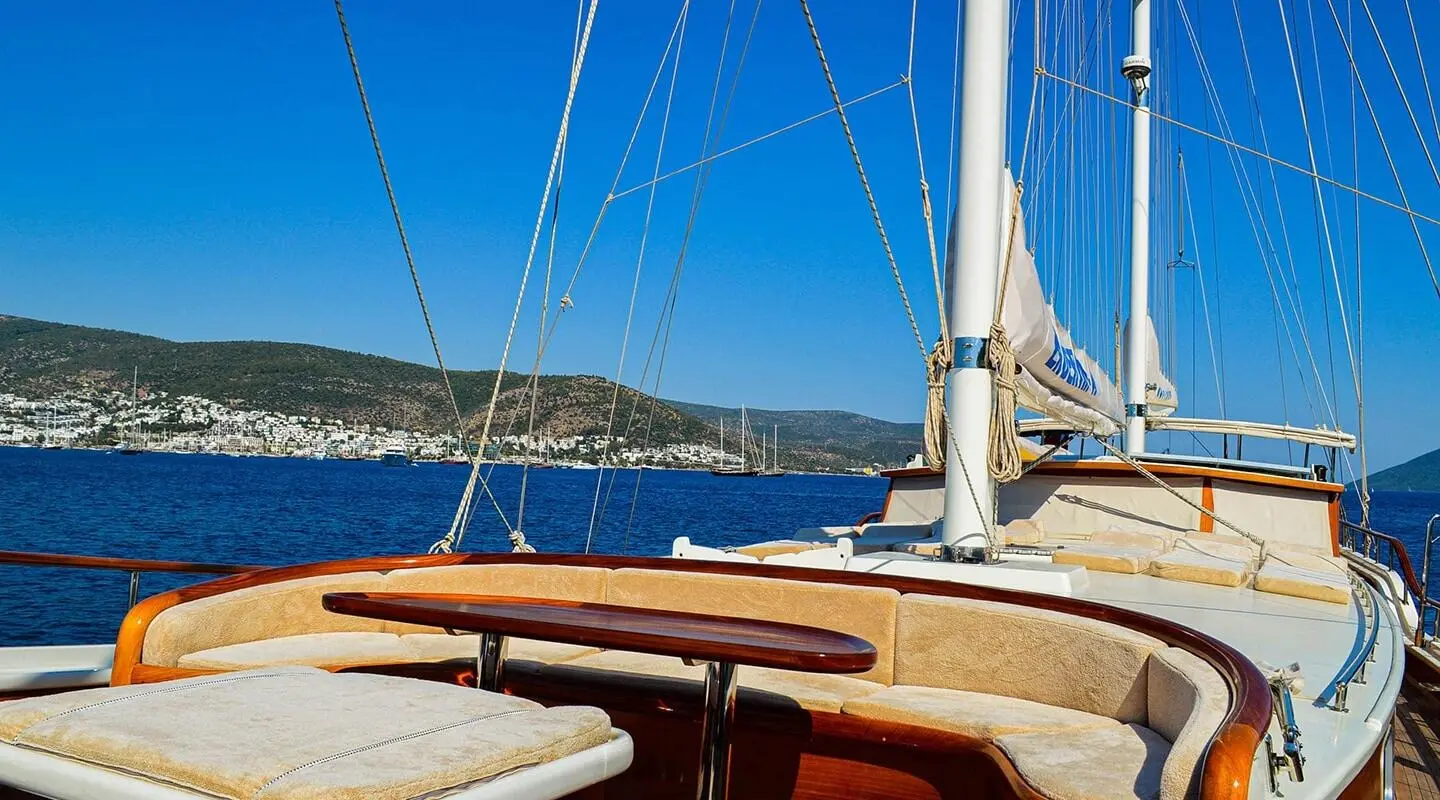 Enderim A yacht deck with cream cushions and wooden table against blue sea