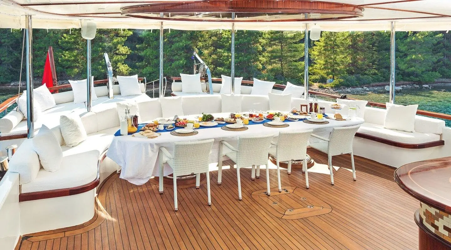 Halcon Del Mar yacht at sunset with long dining table on deck set for guests