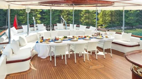 Halcon Del Mar yacht at sunset with long dining table on deck set for guests