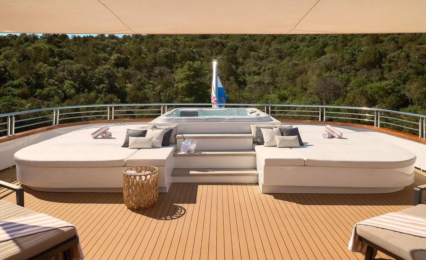 Wide deck with white seating and cushions, trees in the background