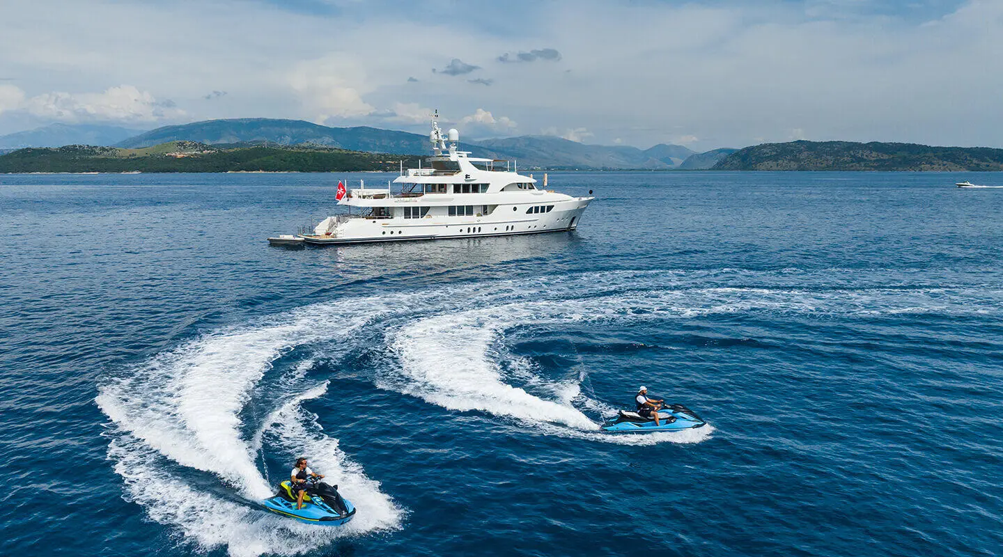 Serenity yacht sailing on blue sea with wake, sleek white hull, clear sky